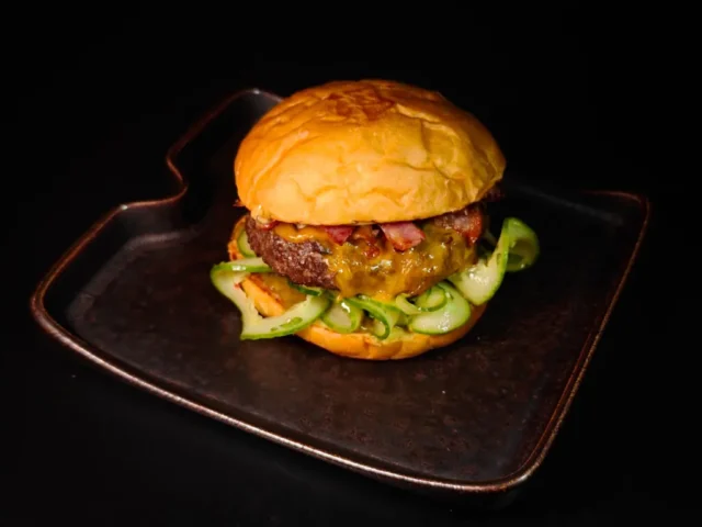 Burger with bacon, smashed cucumbers and jalapeno sauce